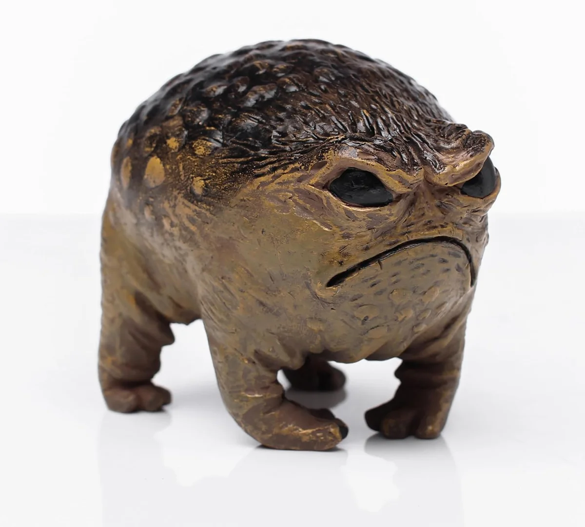 Small outdoor garden statue of a deliberately ugly, scowling brown-green toad with a wide angry mouth, bulging eyes and warty skin, cast in resin and sized to sit on a shelf or in a flowerbed as a novelty yard decoration